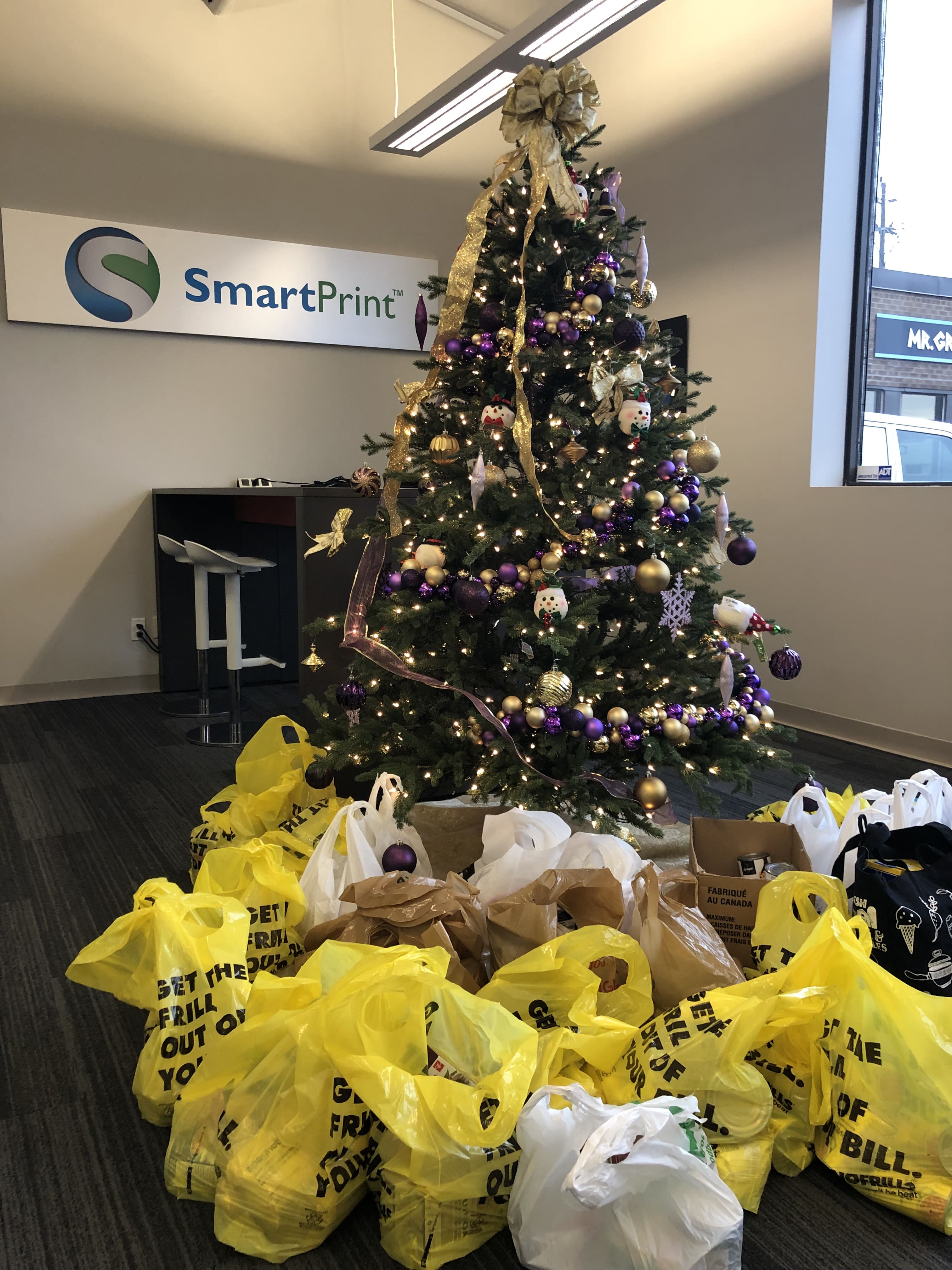 grocery bags under the smartprint christmas tree for the winter food drive